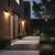 Exterior wall lights placed on the patio walls of a modern house giving out a warm glow at dusk.